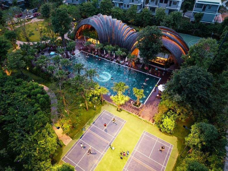 A swimming pool and tennis courts in a park Description automatically generated